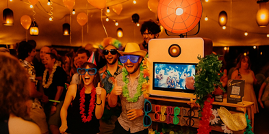 Photobooth huren โ lach, klik & print | Partyverhuur-Verkoop Bruidspaar en vrienden poseren bij photobooth met props en gepersonaliseerde fotostrip